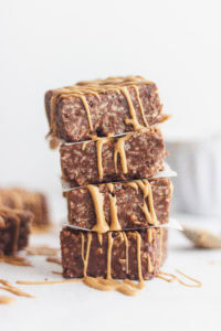 A stack of no bake peanut butter and chocolate marshmallow treats with a peanut butter drizzle