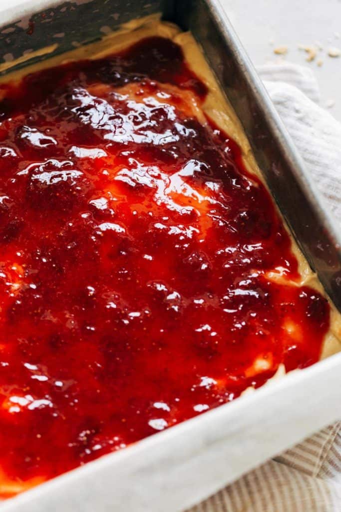 a layer of homemade strawberry jam spread on top of a layer of peanut butter cheesecake
