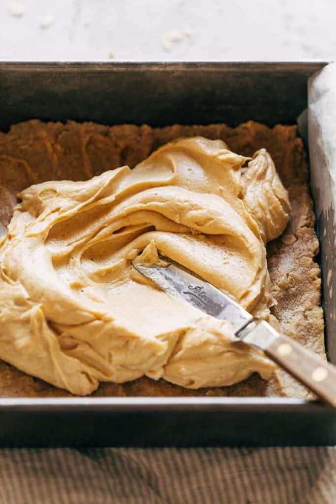 spreading peanut butter cheesecake batter in a pan