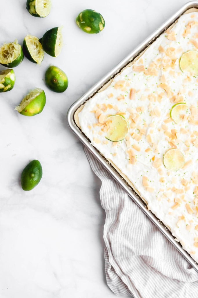 Coconut and lime sheet cake next to squeezed limes