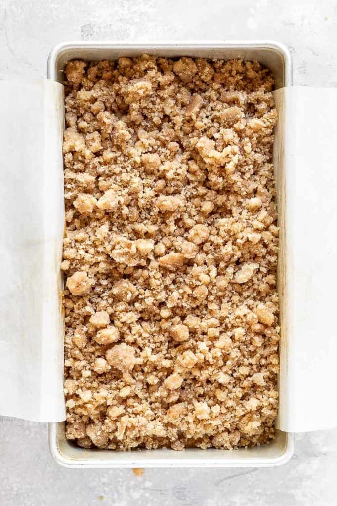 a loaf pan filled with pumpkin bread batter and streusel topping