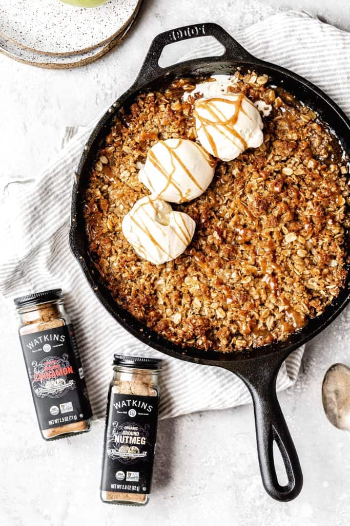 a cast iron skillet of apple crisp with ice cream on top