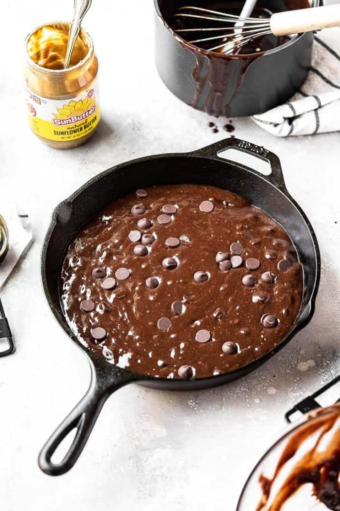 brownie batter ready to bake in a cast iron skillet