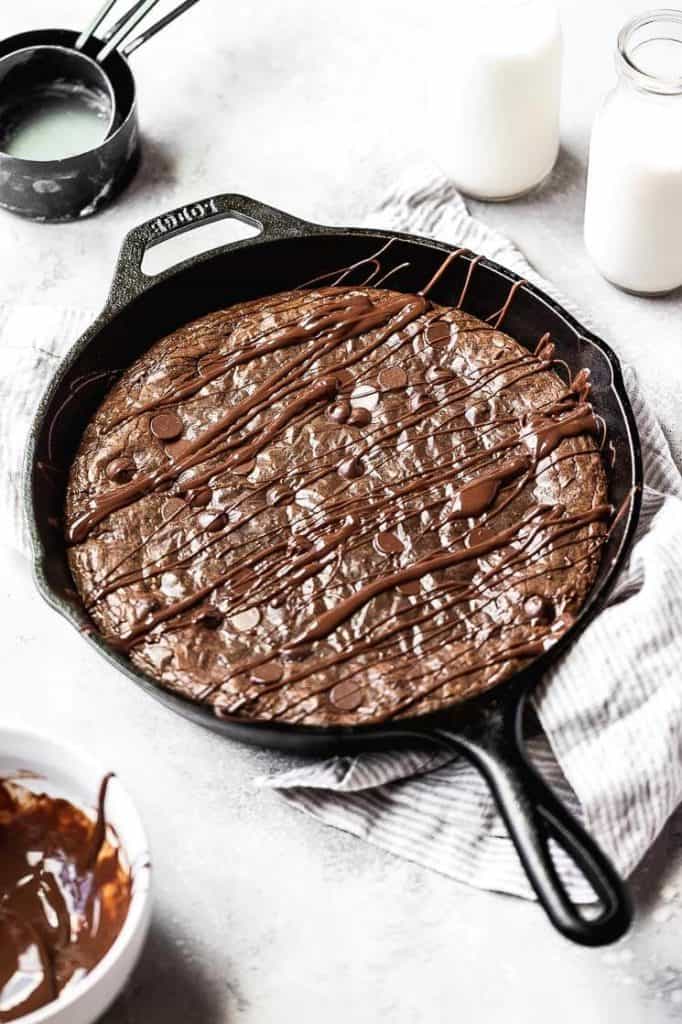 skillet brownies in a cast iron skillet with a chocolate drizzle