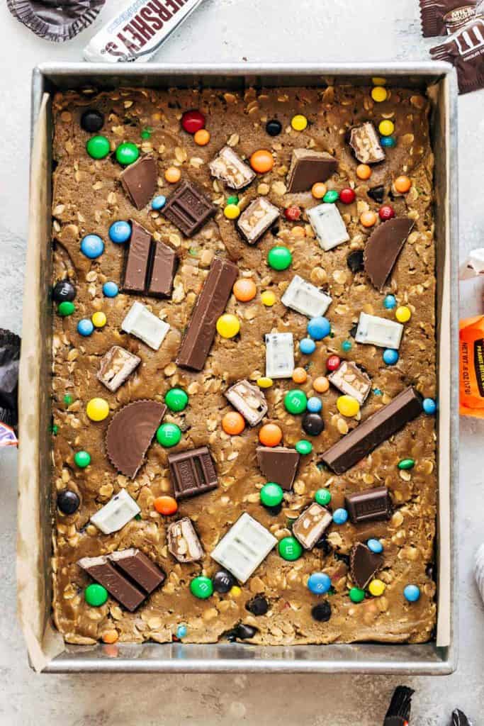cookie dough pressed into a pan with halloween candy on top