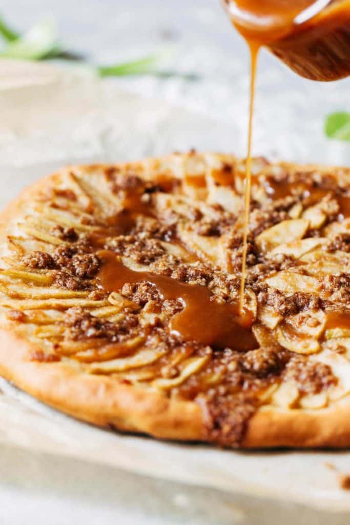 caramel being drizzled onto a caramel apple dessert pizza