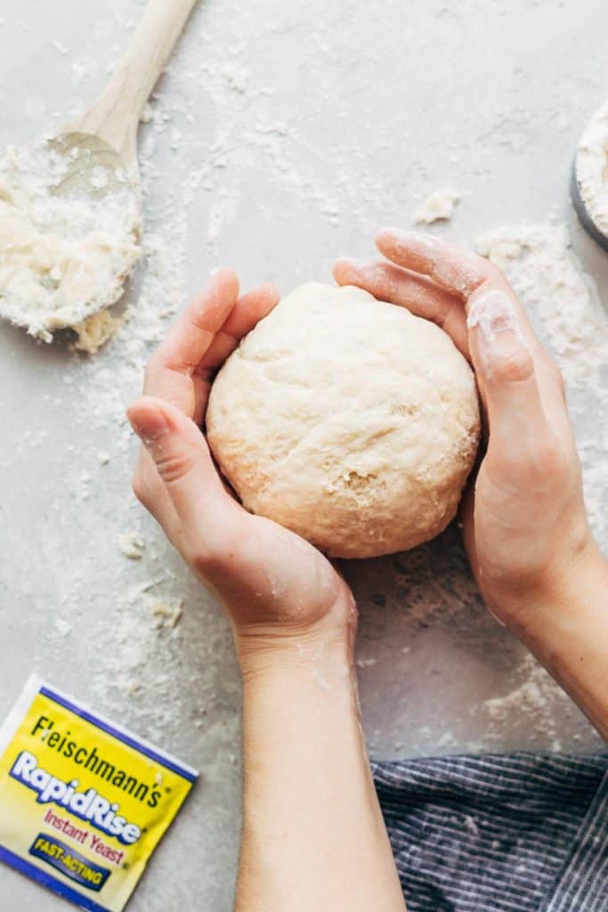 pizza dough rolled into a ball using two hands
