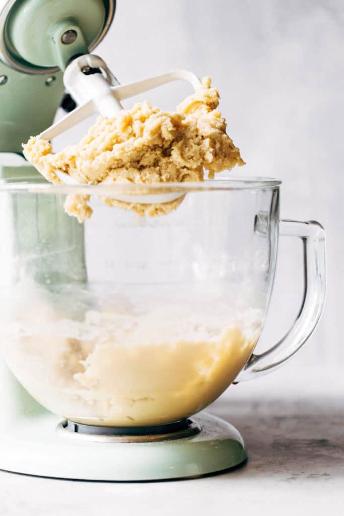 a stand mixer tilted back with sugar cookie dough on the paddle attachment