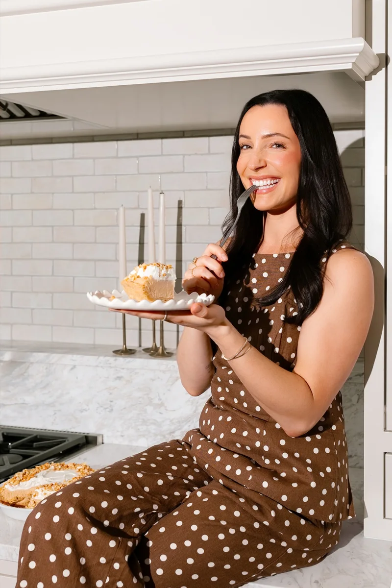 Jenna holding a slice of pie in her kitchen