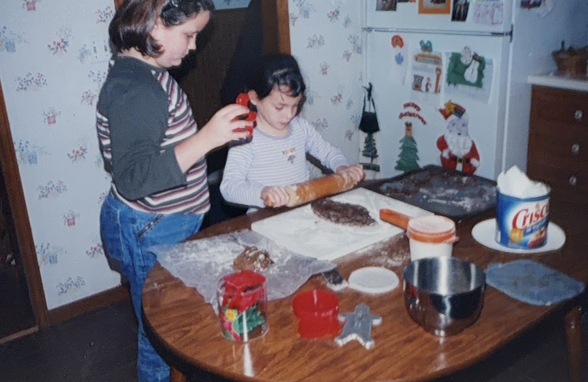 Two children baking gingerbread cookies at a kitchen table
