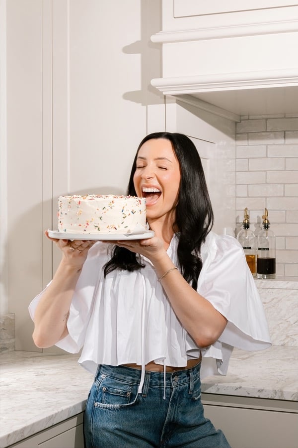 Jenna holding a sprinkle cake in her kitchen