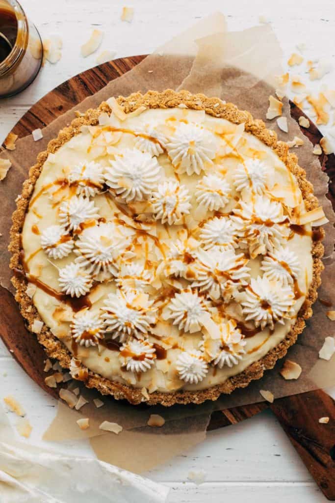 the top of a coconut cream pie pipped with whipped cream and drizzled with caramel sauce