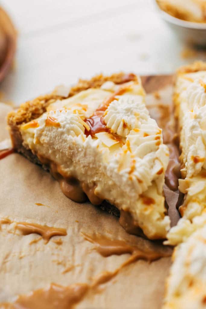 close up on a slice of coconut cream pie with a layer of caramel on the bottom