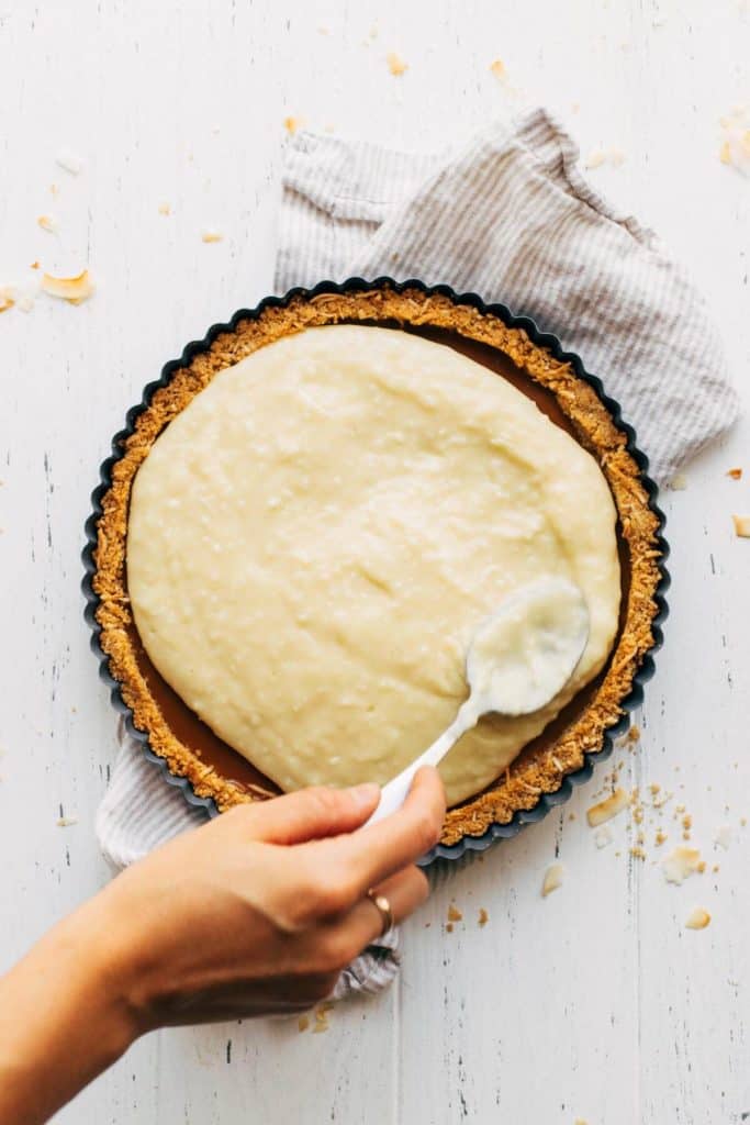 spreading an even layer of coconut cream pie filling into a pie shell