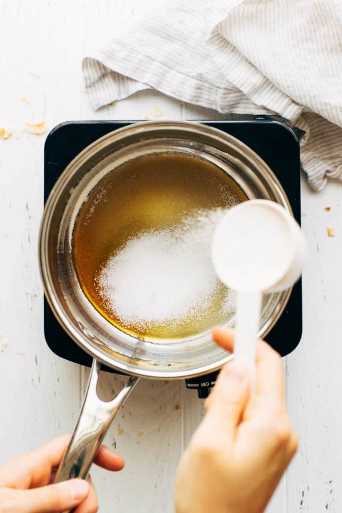 sprinkling sugar on top of a layer of melted sugar in a saucepan