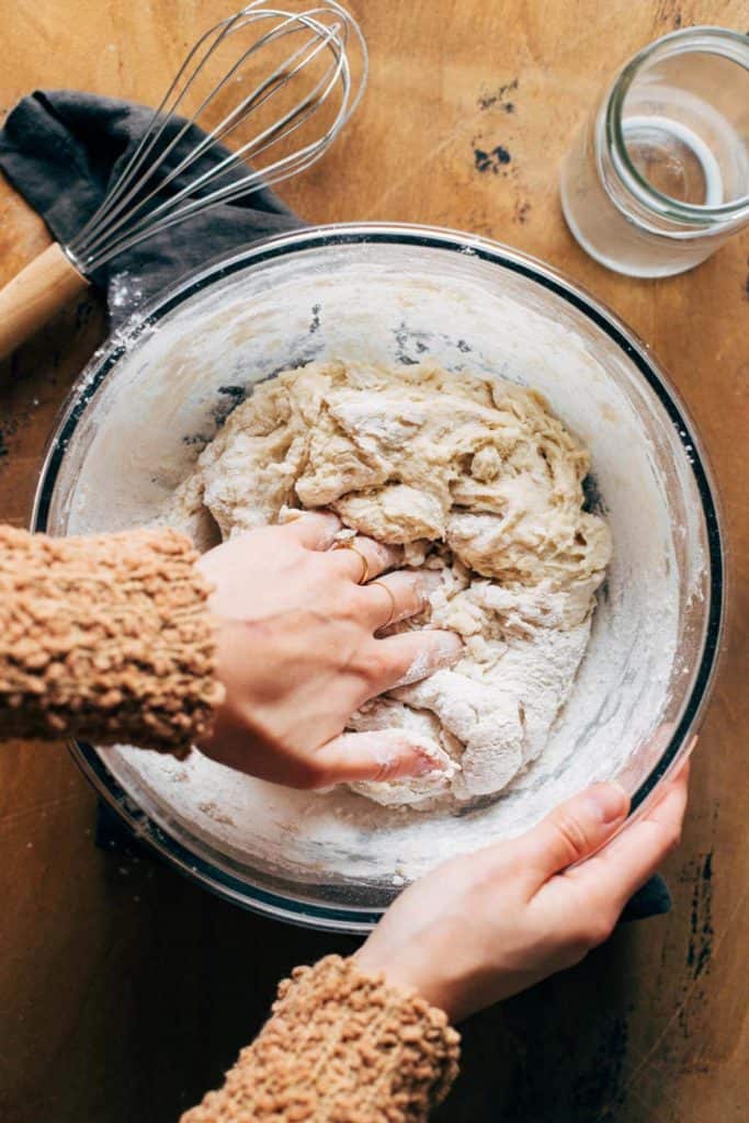 kneading cinnamon roll dough inside a bowl