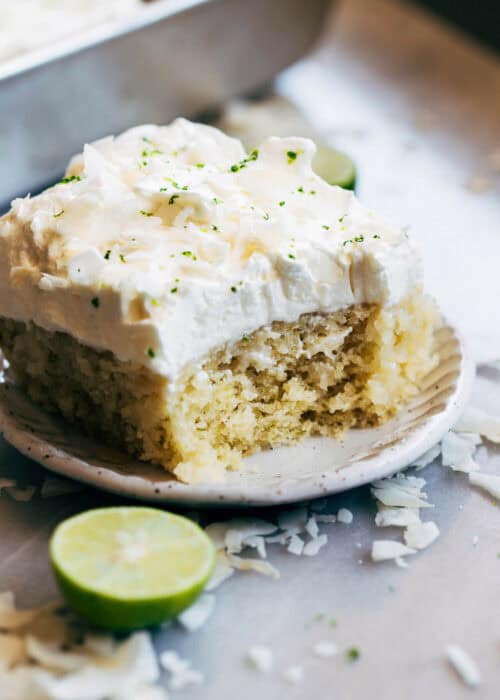 A slice of coconut soaked lime cake with a bite taken out.