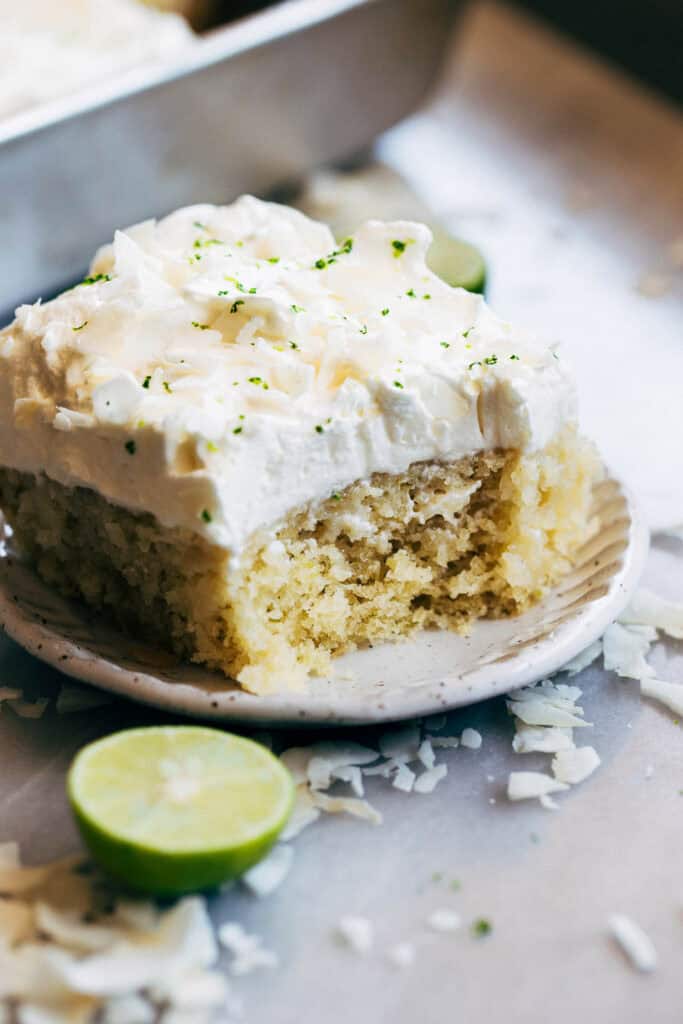 A slice of coconut soaked lime cake with a bite taken out.