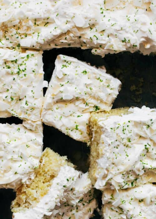 Sliced squares of lime cake topped with coconut whipped cream frosting.