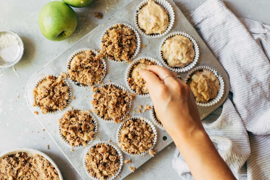 adding crumble to the top of scooped muffin batter