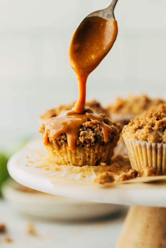 drizzling caramel on top of an apple crumble muffin