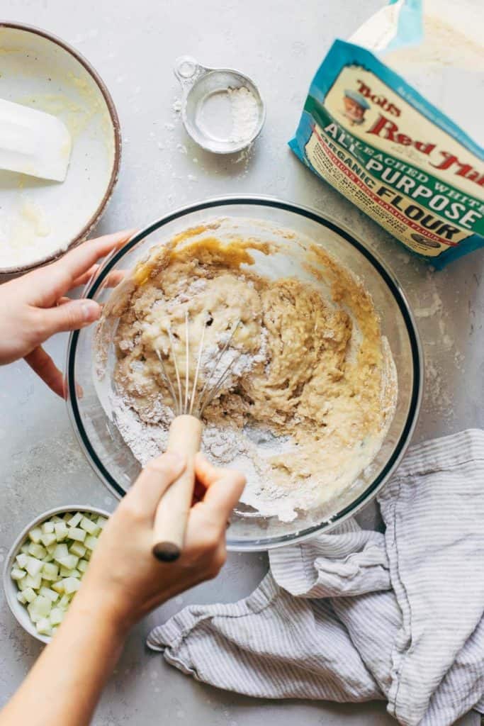 mixing together wet and dry ingredients for apple muffins