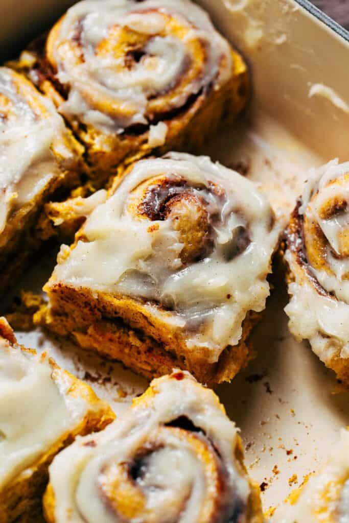 a pumpkin cinnamon roll topped with cream cheese frosting
