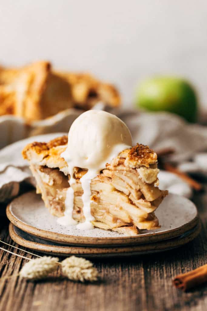 a slice of apple pie on a place topped with melting ice cream