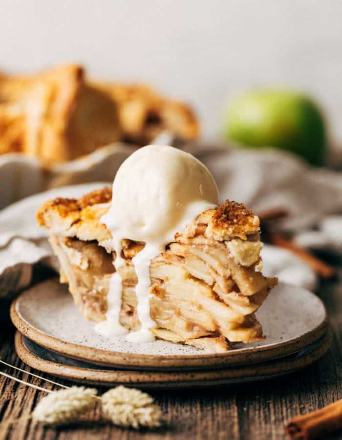a slice of apple pie on a place topped with melting ice cream