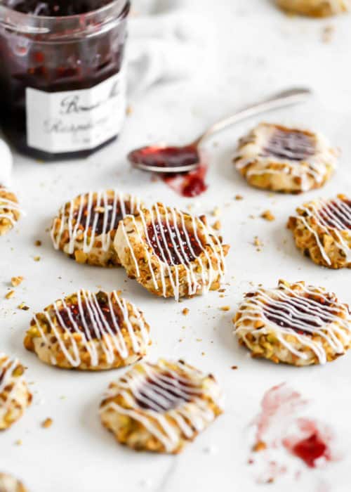 pistachio and raspberry thumbprint cookies on a marble slab