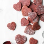 heart shaped shortbread cookies piled on top of parchment paper