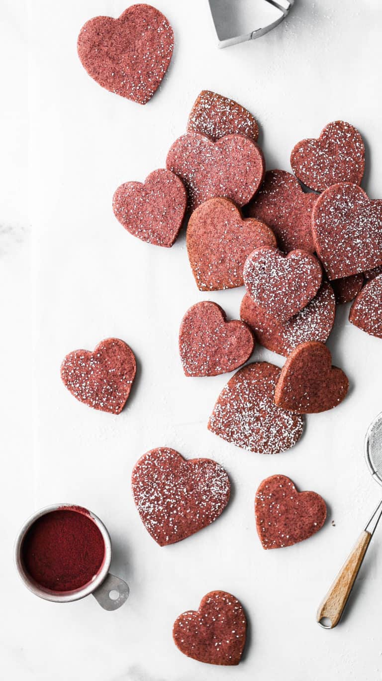 heart shaped shortbread cookies piled on top of parchment paper