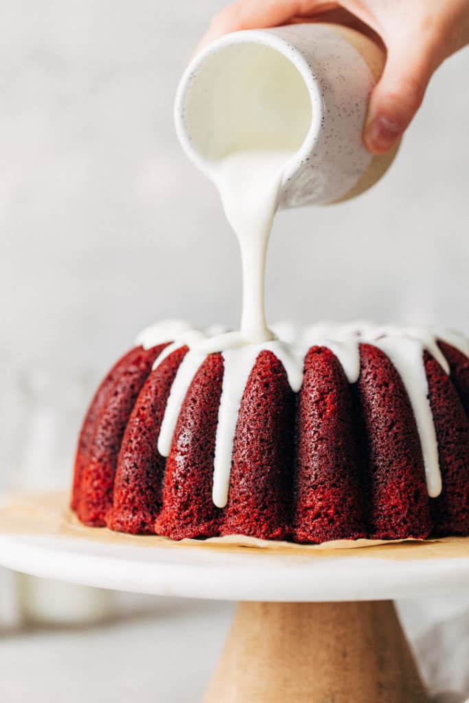 pouring cream cheese glaze on a bundt cake
