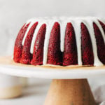 red velvet bundt cake from the side with glaze dripping down