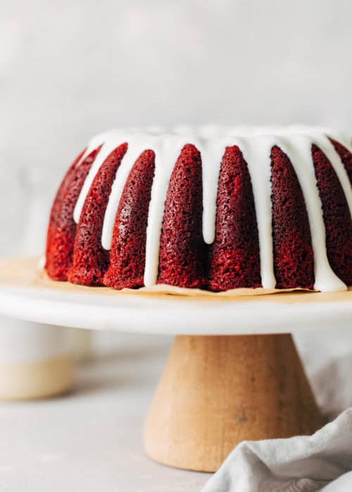 red velvet bundt cake from the side with glaze dripping down