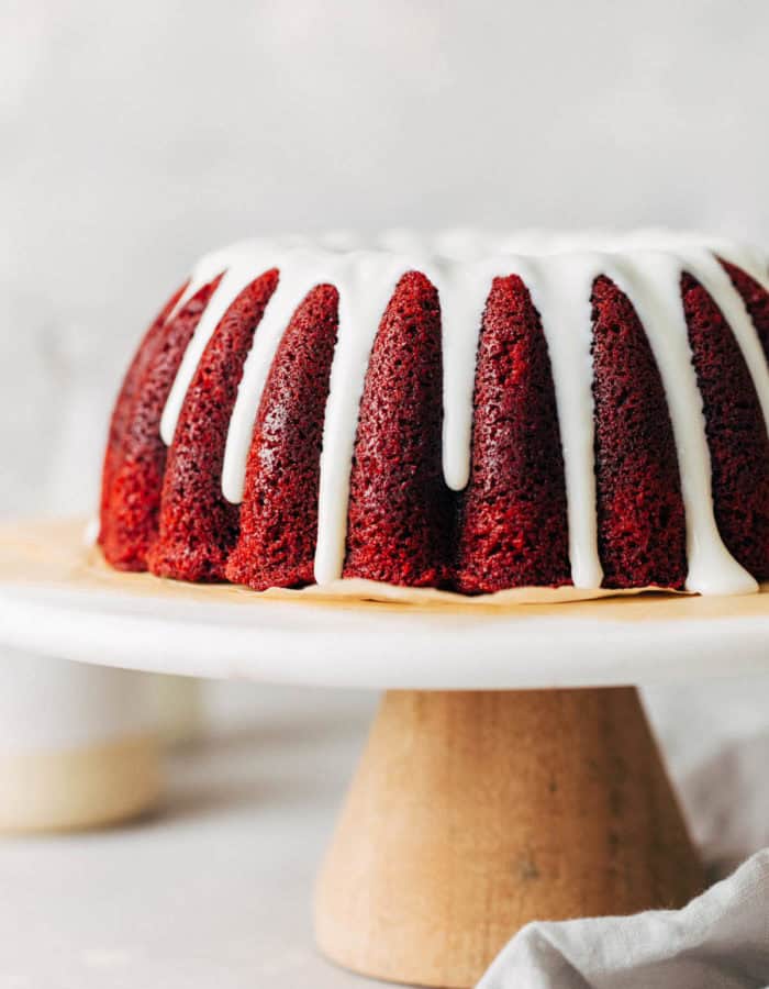 red velvet bundt cake from the side with glaze dripping down