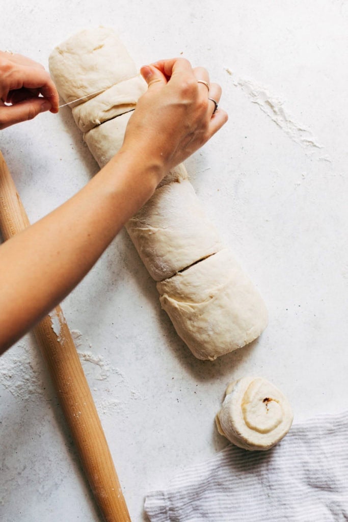 slicing cinnamon roll dough with floss