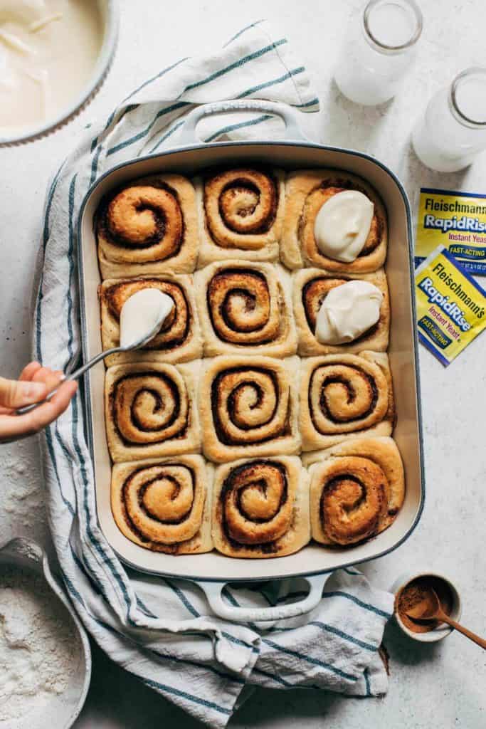 spreading icing on warm cinnamon rolls