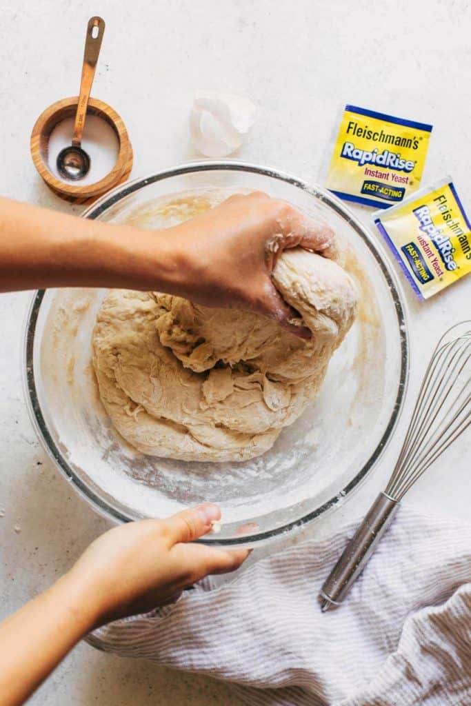 kneading cinnamon roll dough in a bowl