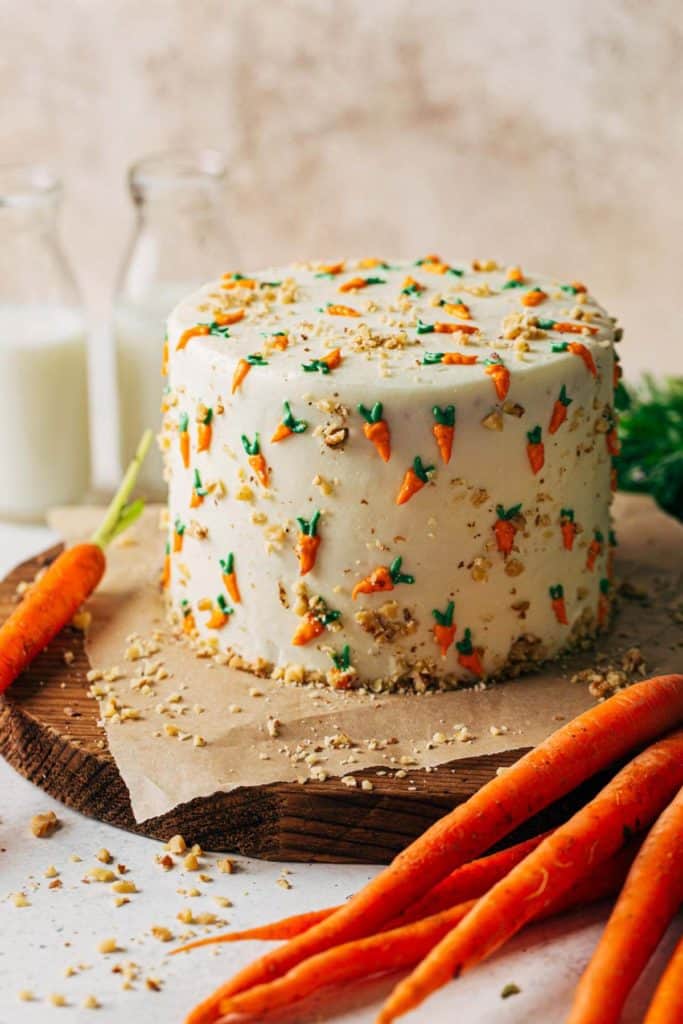 a carrot cake decorated with frosting carrots on a rustic wood board