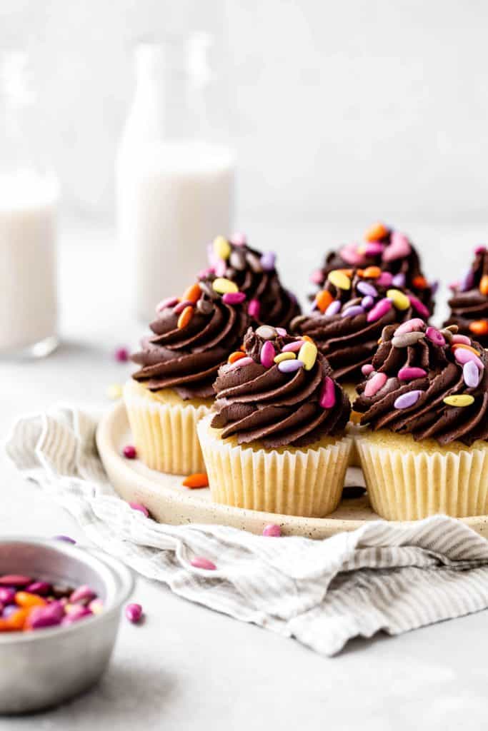 a tray of vanilla cupcakes with chocolate frosting