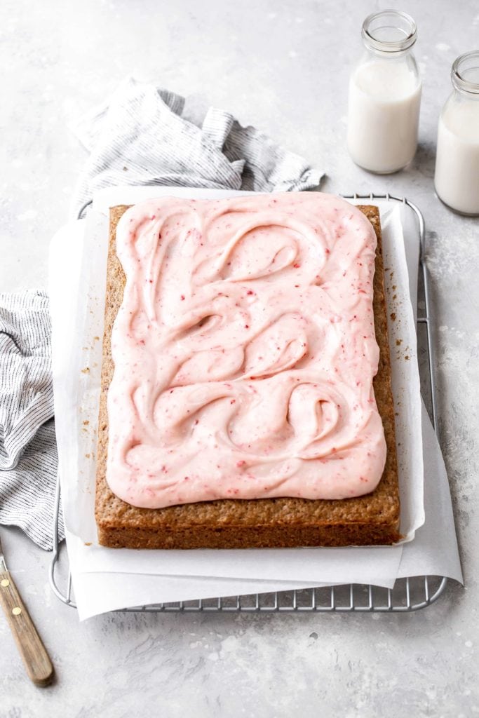a strawberry cake with swirls of strawberry cream cheese frosting on top