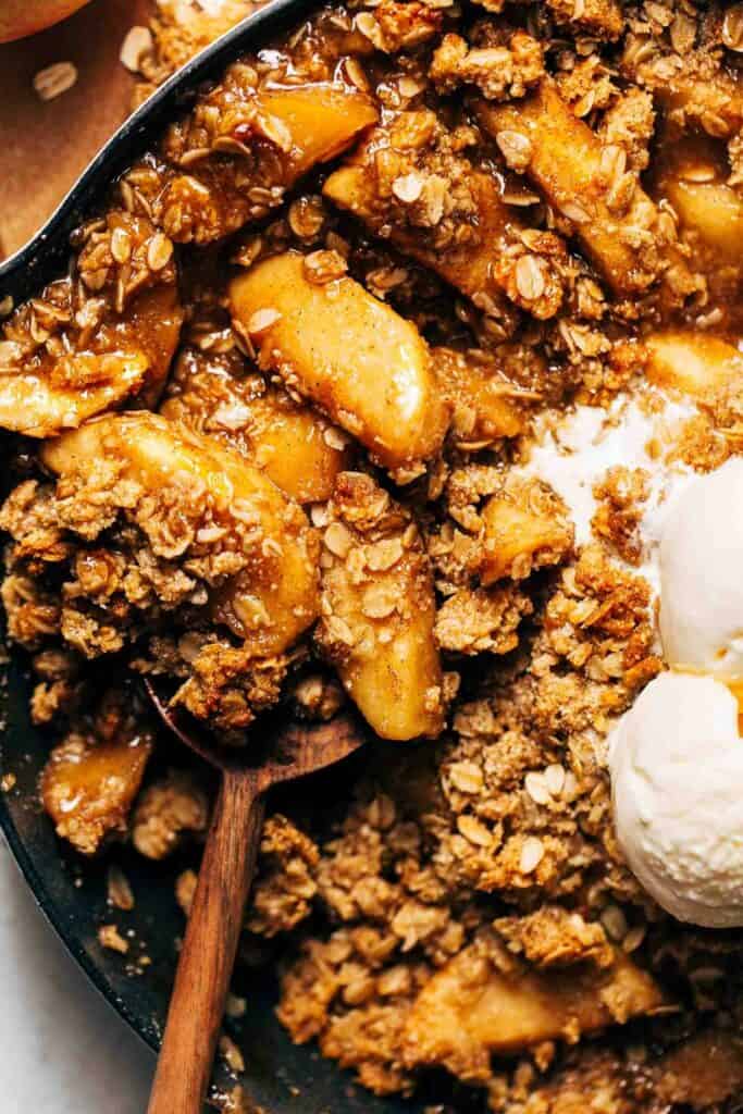 scooping into a skillet of apple crisp