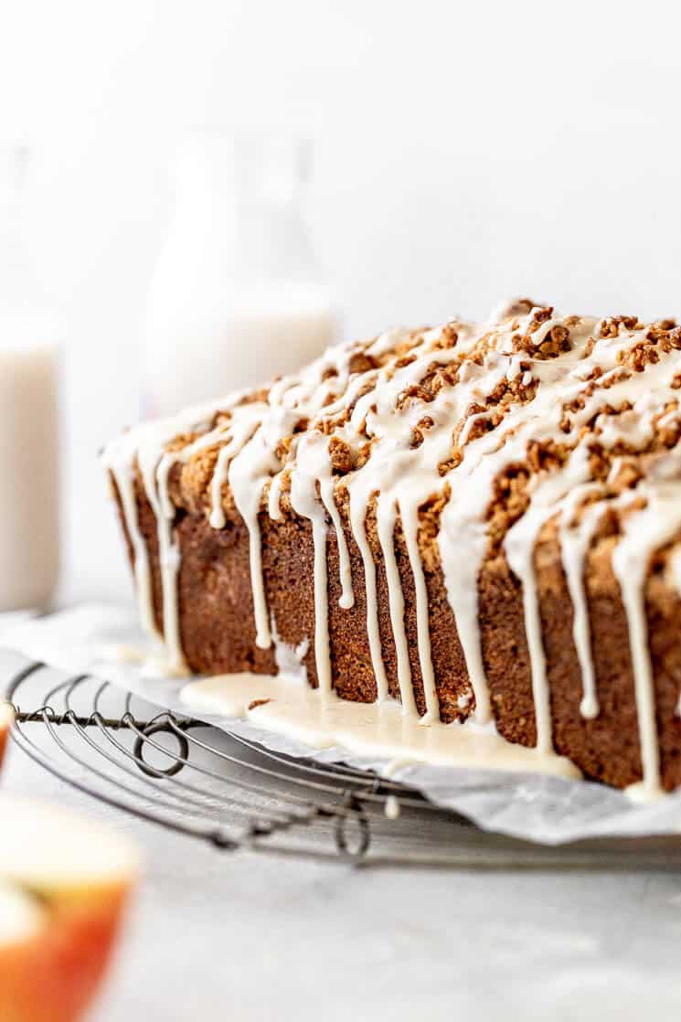 Apple bread on a wire rack with icing dripping down the sides