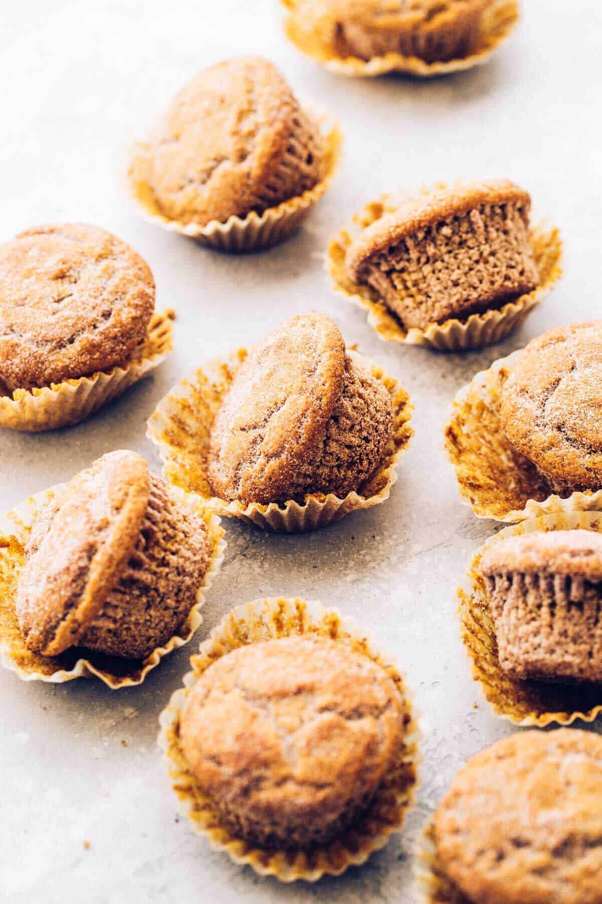 gluten free pumpkin muffins scattered on a board with their wrappers taken off