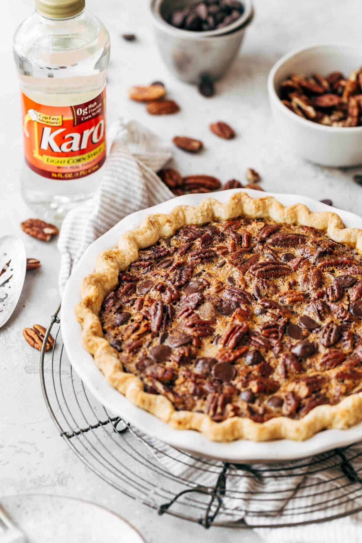 Baked chocolate pecan pie with a bottle of corn syrup in the background.