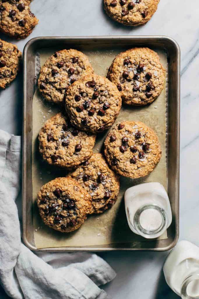 a batch of gluten free oatmeal chocolate chip cookies scattered on a baking tray