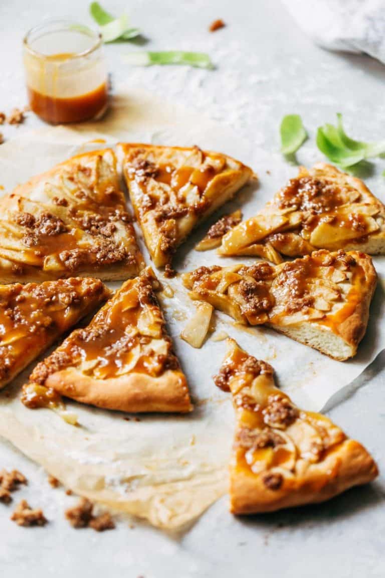 a sliced apple dessert pizza on parchment paper