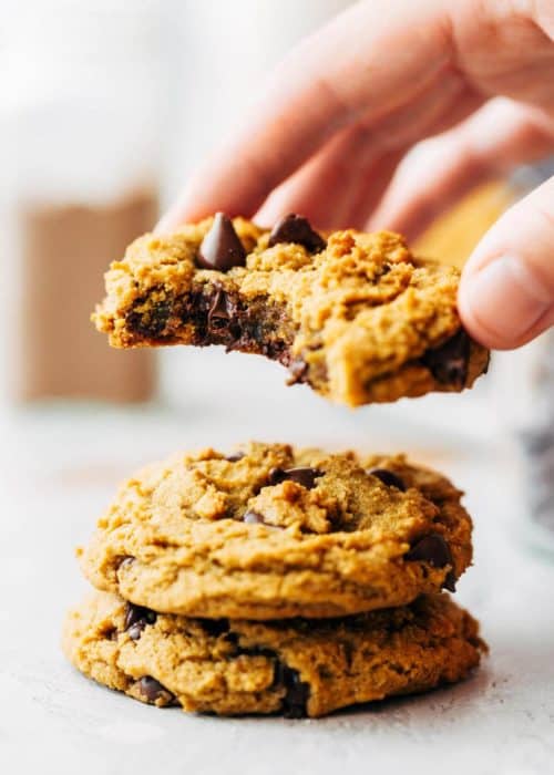 lifting the top cookie from a stack of vegan pumpkin cookies