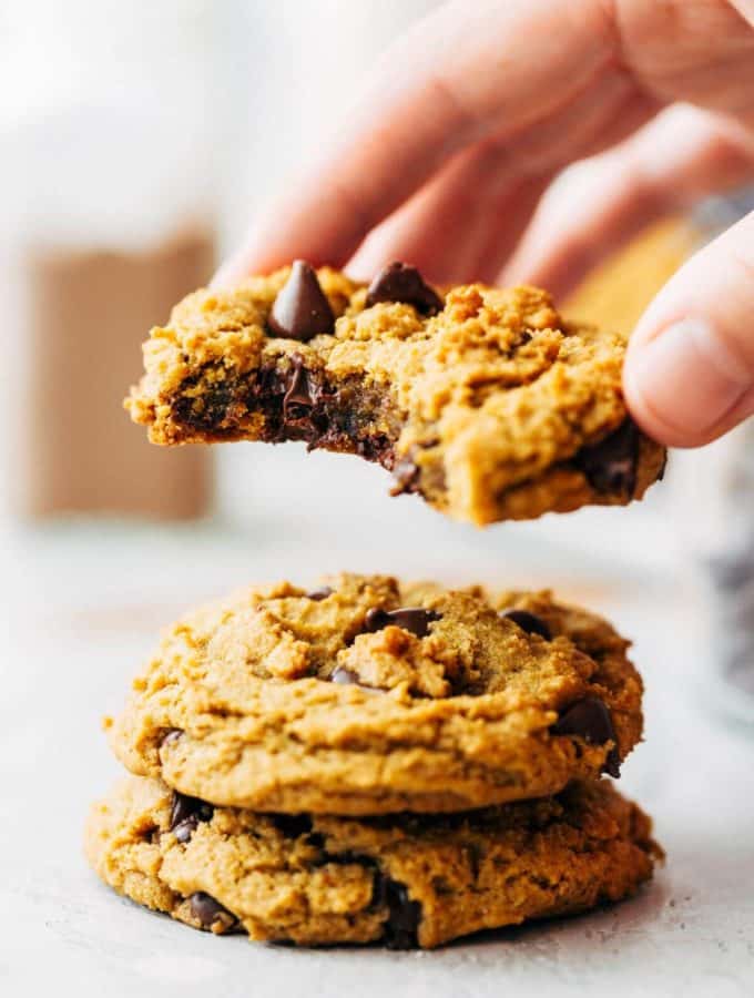 lifting the top cookie from a stack of vegan pumpkin cookies